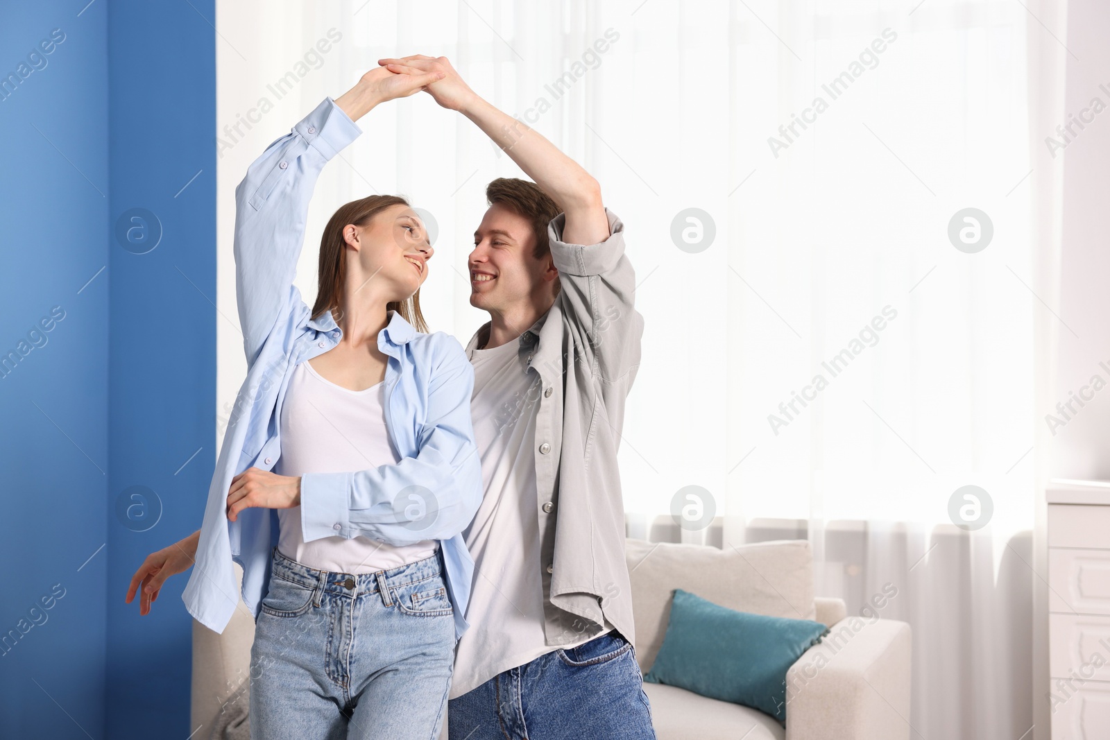 Photo of Happy couple dancing at home. Space for text