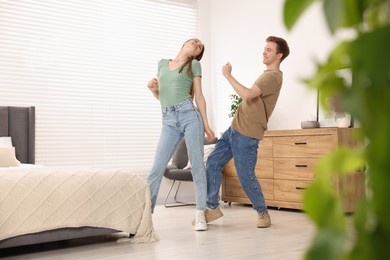 Photo of Happy young couple dancing together in bedroom
