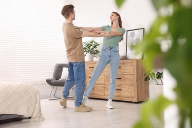 Photo of Carefree young couple dancing together at home