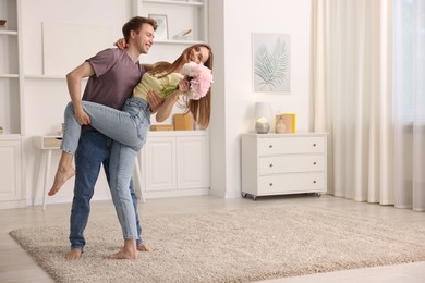 Photo of Happy young couple dancing together at home. Space for text