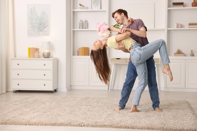 Photo of Happy young couple dancing together at home. Space for text