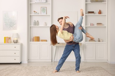 Photo of Young couple dancing together at home. Space for text
