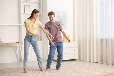 Photo of Happy young couple dancing together at home. Space for text