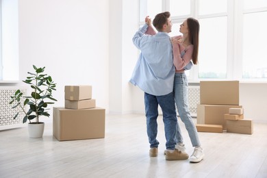 Photo of Young couple dancing and cardboard boxes at home. Moving day