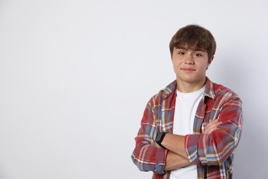 Photo of Cute teenage boy with crossed arms on light grey background. Space for text