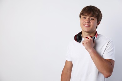 Photo of Portrait of smiling teenage boy with headphones on light grey background. Space for text