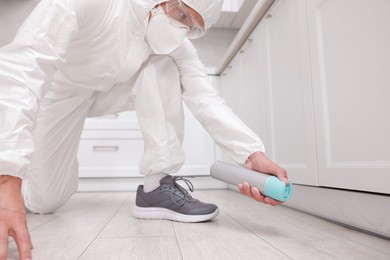 Photo of Pest control worker in protective suit spraying insecticide at home, closeup
