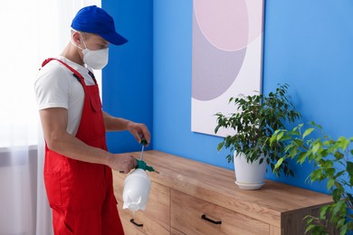Photo of Pest control worker spraying insecticide at home