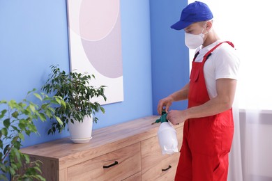 Photo of Pest control worker spraying insecticide at home