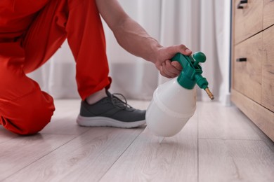 Photo of Pest control worker spraying insecticide at home, closeup