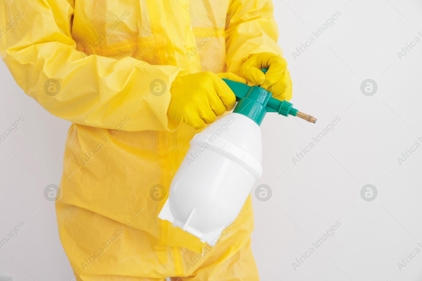 Pest control worker in protective suit spraying insecticide near white wall, closeup Photo of Pest control worker in protective suit spraying insecticide near white wall, closeup
