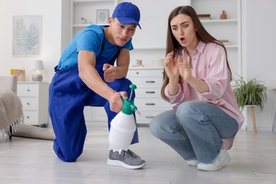 Photo of Worried woman and pest control worker spraying insecticide at home