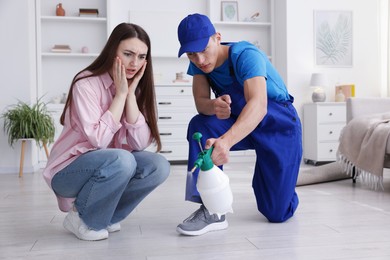 Photo of Worried woman and pest control worker spraying insecticide at home