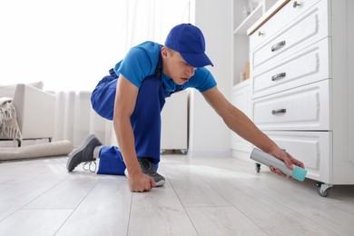 Photo of Pest control worker spraying insecticide at home