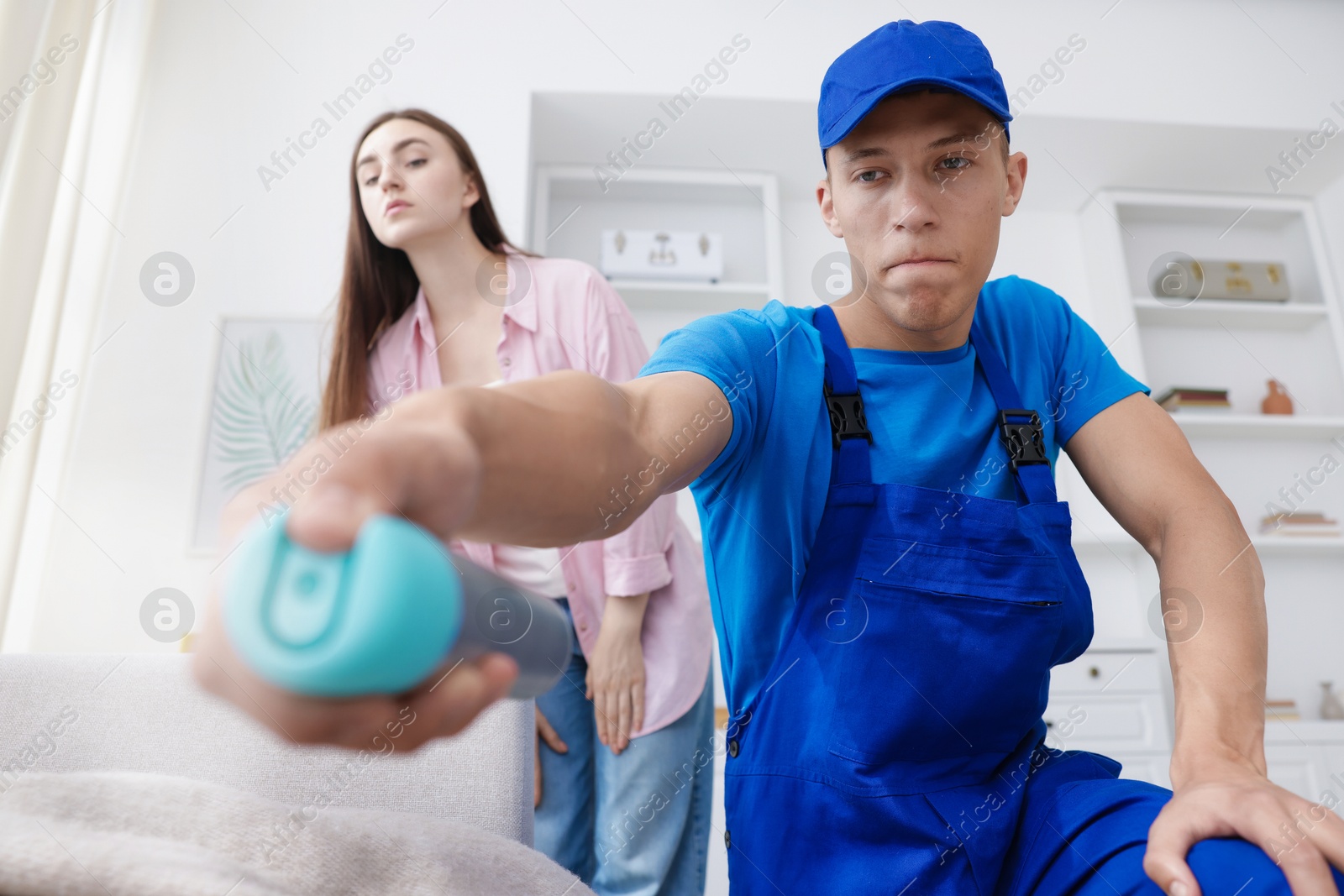 Worried woman and pest control worker spraying insecticide at home Photo of Worried woman and pest control worker spraying insecticide at home