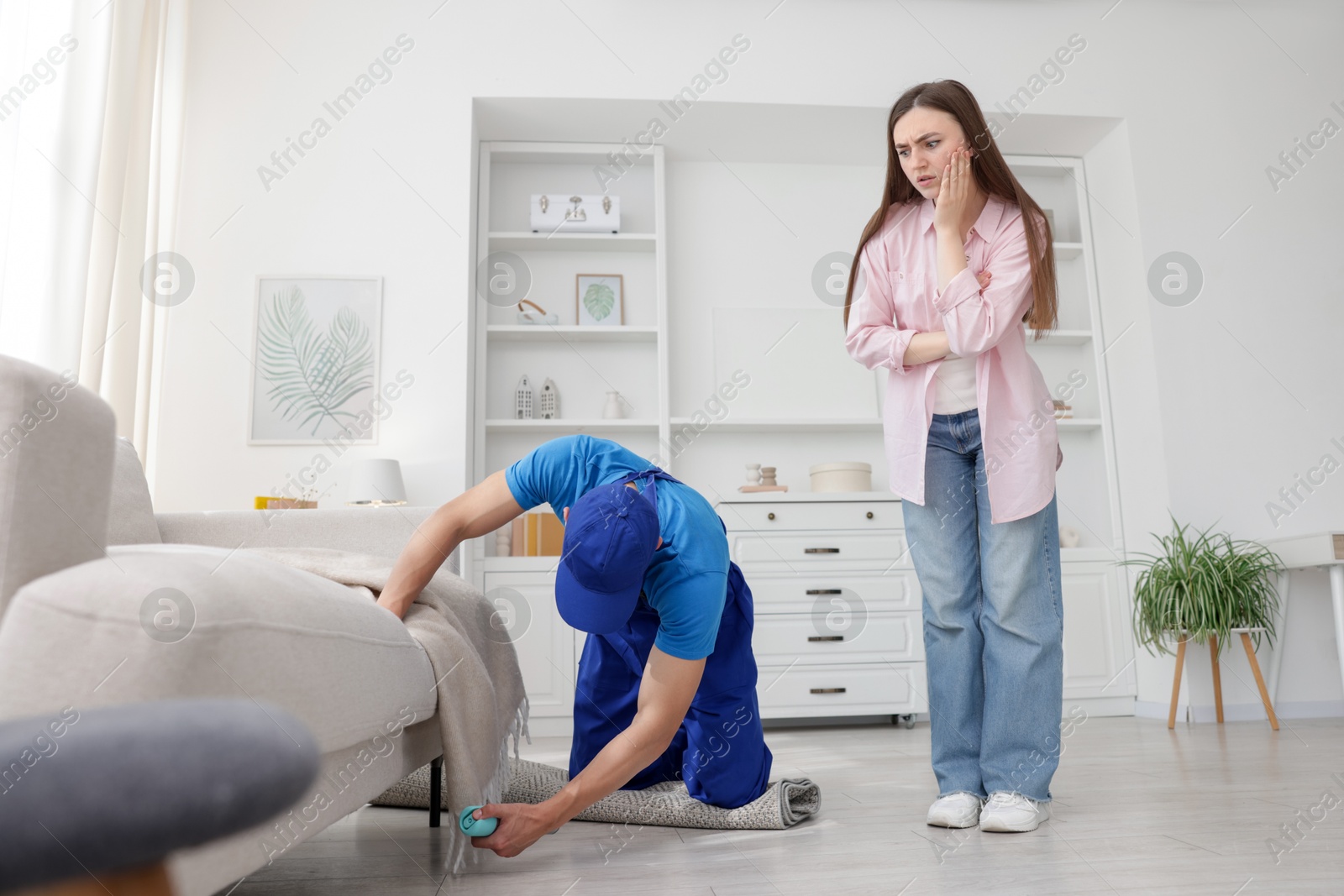 Worried woman and pest control worker spraying insecticide at home Photo of Worried woman and pest control worker spraying insecticide at home