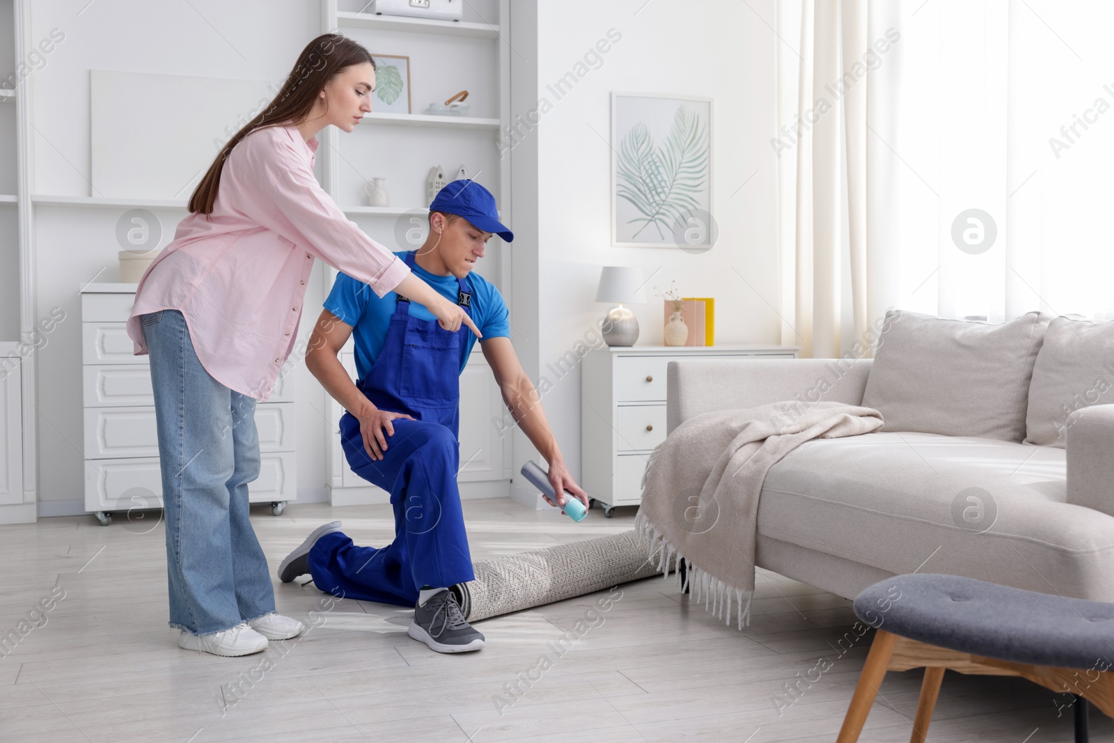 Worried woman and pest control worker spraying insecticide at home Photo of Worried woman and pest control worker spraying insecticide at home