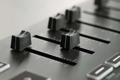 Photo of MIDI keyboard with faders on light background, closeup