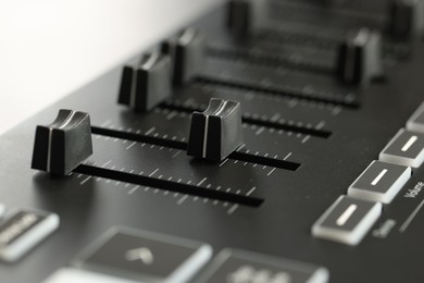 Photo of MIDI keyboard with faders on light background, closeup