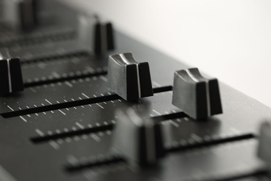 Photo of MIDI keyboard with faders on light background, closeup
