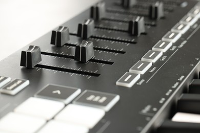 Photo of MIDI keyboard with faders on light background, closeup