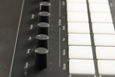 Photo of MIDI keyboard with buttons and faders on table, closeup
