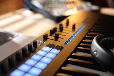 Photo of MIDI keyboard with faders on table indoors, closeup