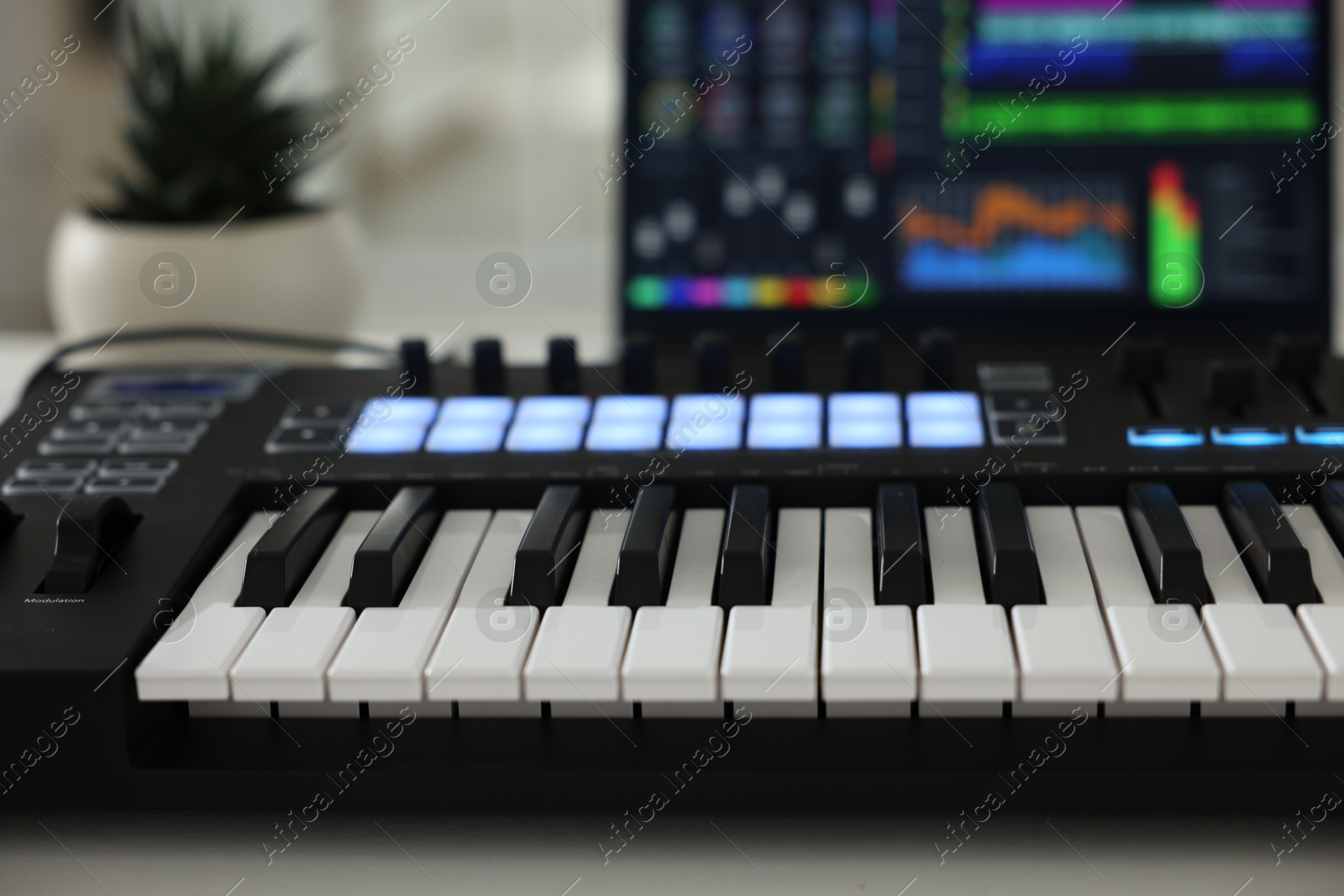 MIDI keyboard and laptop on table indoors, closeup Photo of MIDI keyboard and laptop on table indoors, closeup