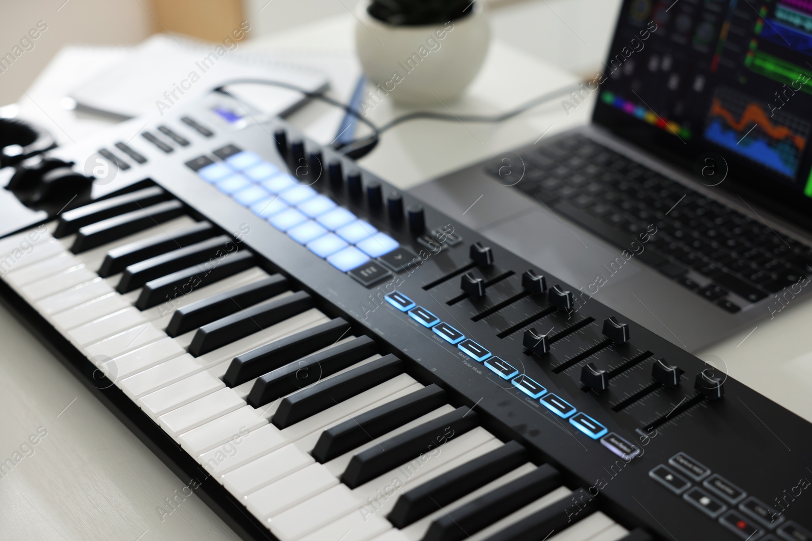 MIDI keyboard and laptop on white wooden table, closeup Photo of MIDI keyboard and laptop on white wooden table, closeup