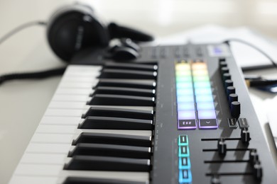 Photo of MIDI keyboard and headphones on white table, closeup