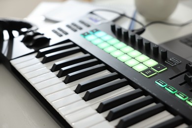 Photo of MIDI keyboard on white wooden table, closeup