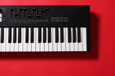 Photo of One portable MIDI keyboard on red background, top view