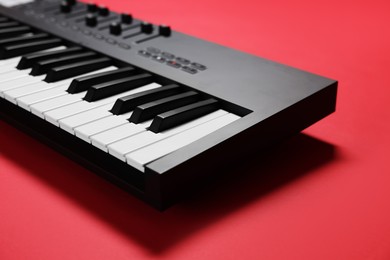 Photo of One portable MIDI keyboard on red background, closeup