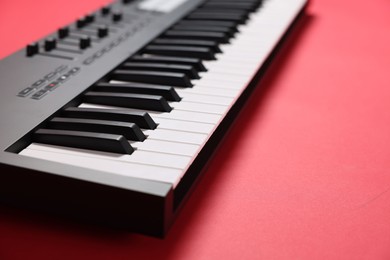 Photo of One portable MIDI keyboard on red background, closeup. Space for text