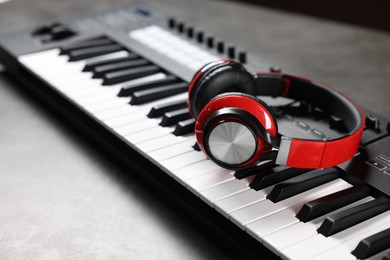 Photo of MIDI keyboard and headphones on grey table, closeup