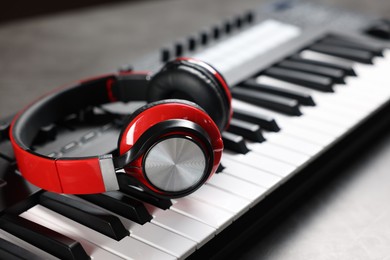 Photo of MIDI keyboard and headphones on grey table, closeup