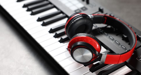 Photo of MIDI keyboard and headphones on grey table, closeup