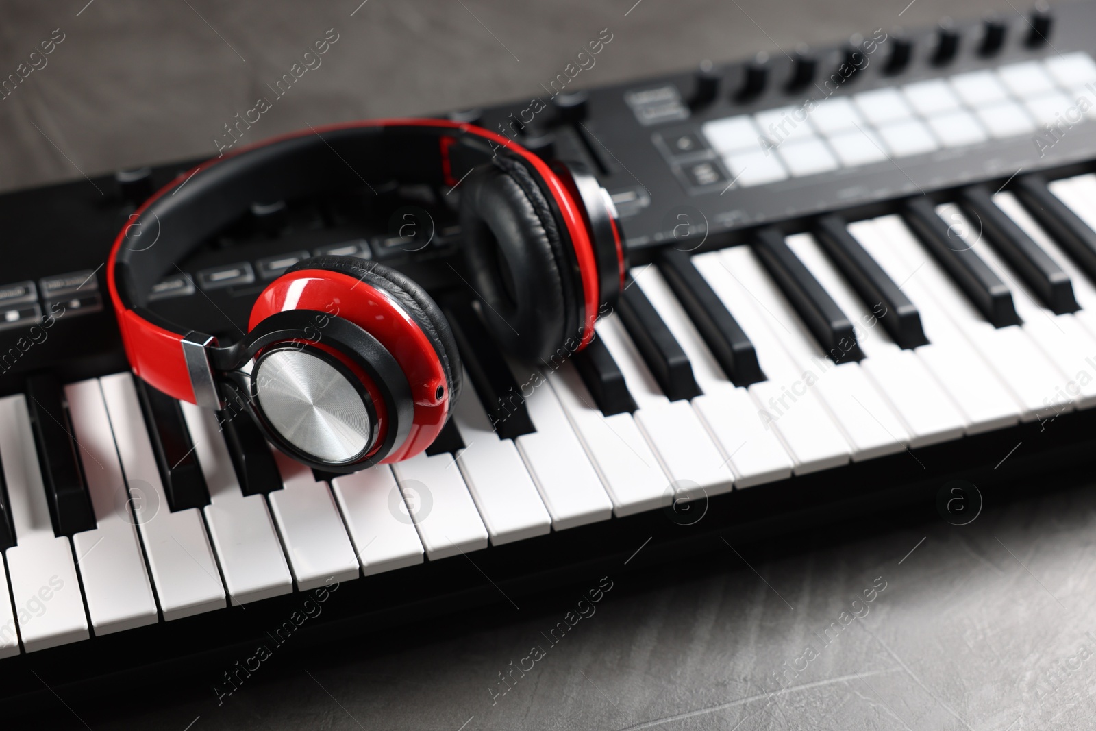 MIDI keyboard and headphones on grey table, closeup Photo of MIDI keyboard and headphones on grey table, closeup