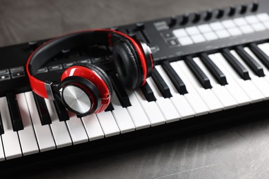 Photo of MIDI keyboard and headphones on grey table, closeup