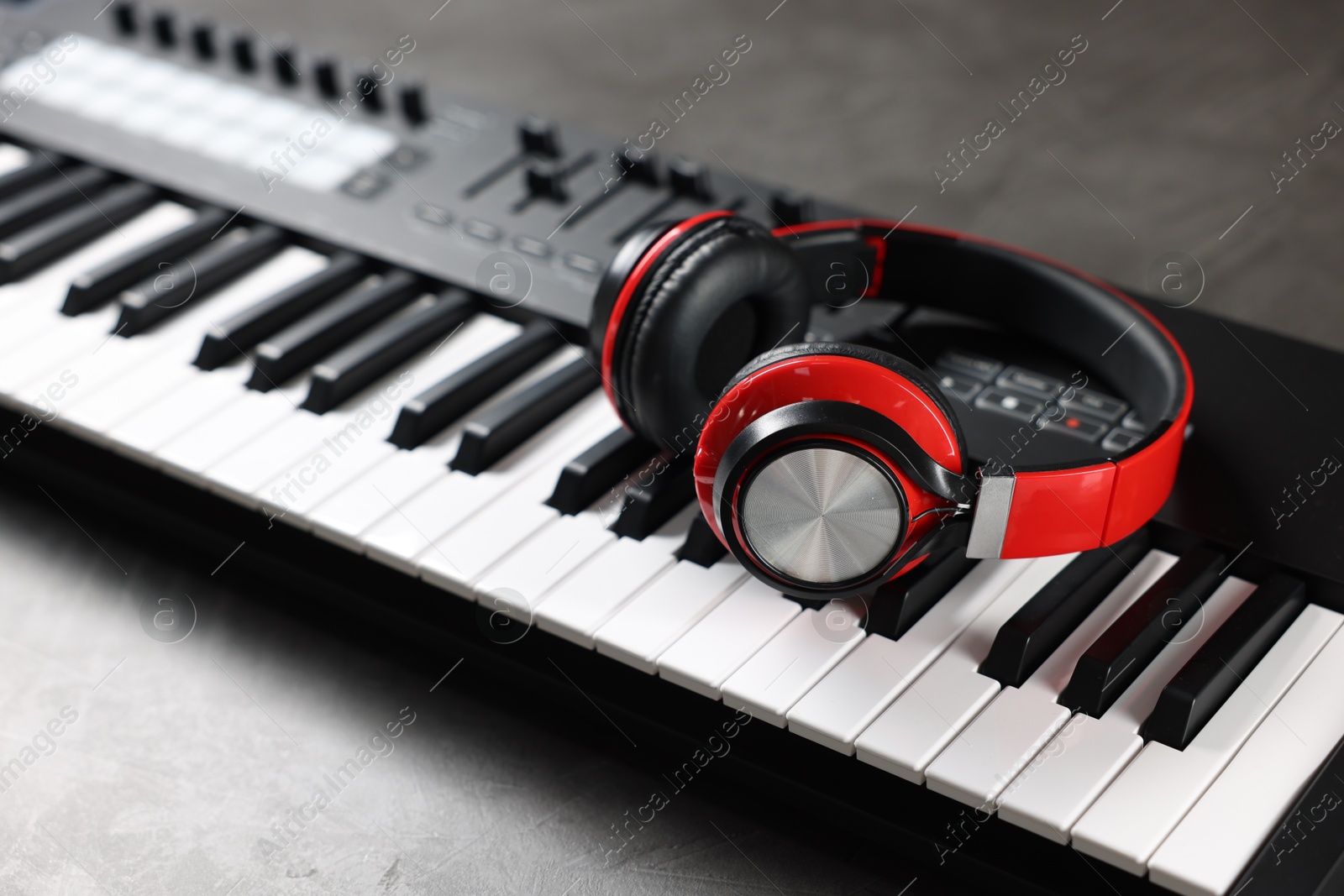 MIDI keyboard and headphones on grey table, closeup Photo of MIDI keyboard and headphones on grey table, closeup