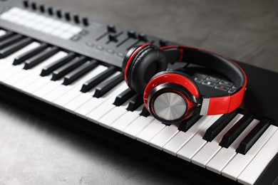 Photo of MIDI keyboard and headphones on grey table, closeup