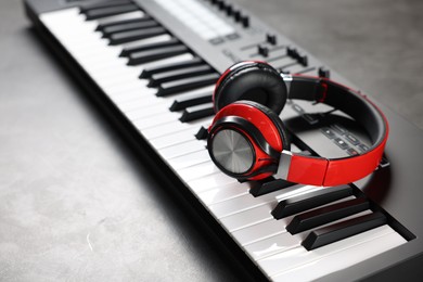 Photo of MIDI keyboard and headphones on grey table, closeup