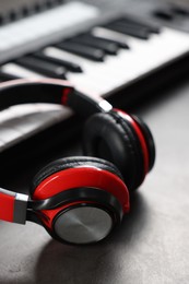 Photo of MIDI keyboard and headphones on grey table, closeup