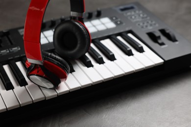 Photo of MIDI keyboard and headphones on grey table, closeup