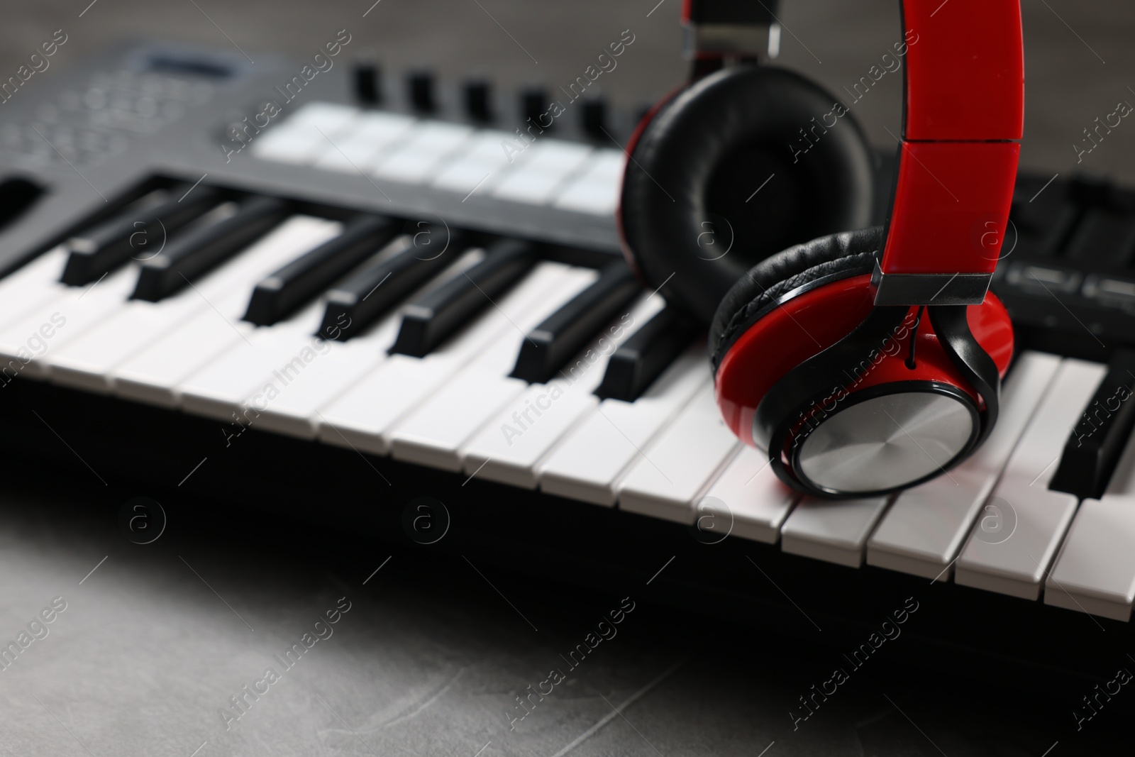 MIDI keyboard and headphones on grey table, closeup Photo of MIDI keyboard and headphones on grey table, closeup