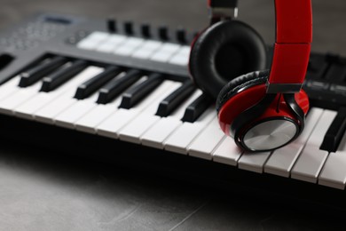 Photo of MIDI keyboard and headphones on grey table, closeup