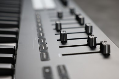 Photo of MIDI keyboard with faders on table, closeup