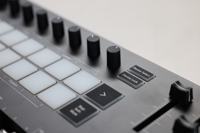 Photo of MIDI keyboard with faders on white table, closeup