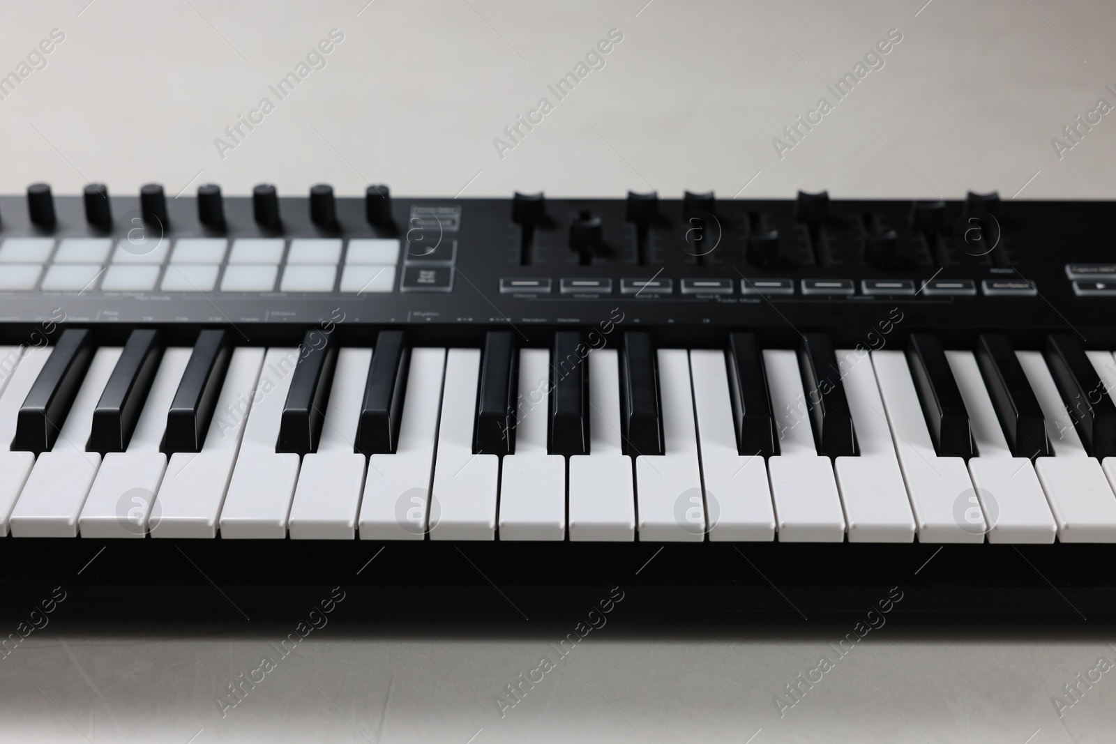 One portable MIDI keyboard on white table, closeup Photo of One portable MIDI keyboard on white table, closeup