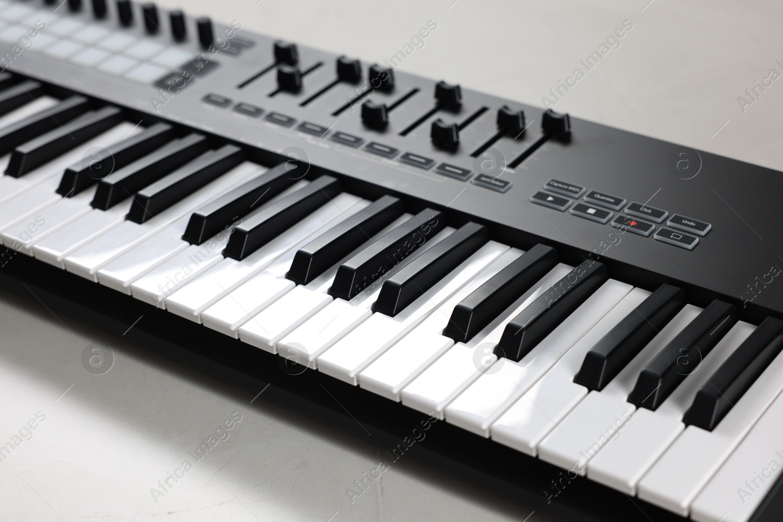 One portable MIDI keyboard on white table, closeup Photo of One portable MIDI keyboard on white table, closeup